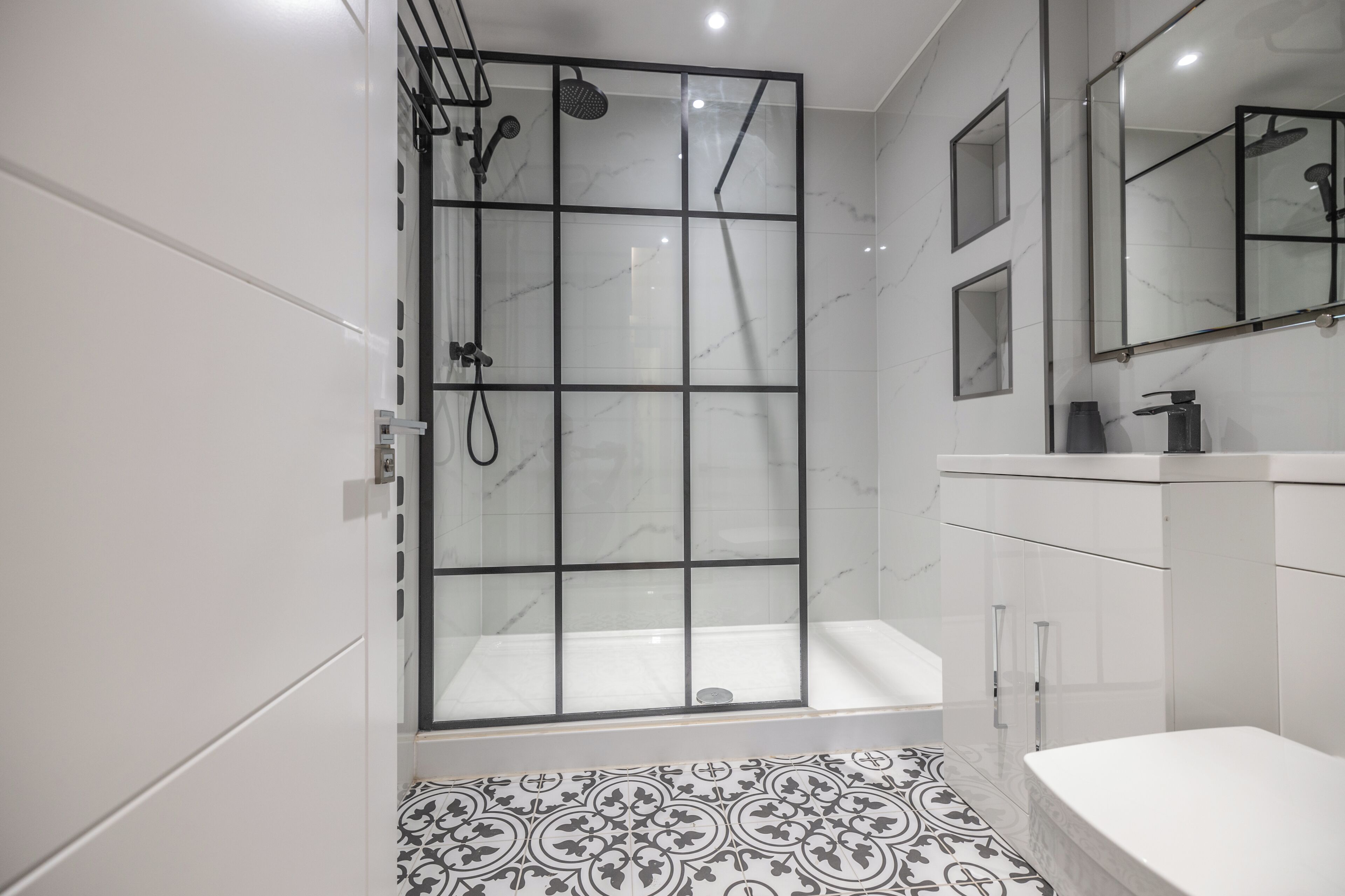 Une salle de bain moderne avec une douche à parois de verre, une baignoire blanche et un carrelage décoratif.