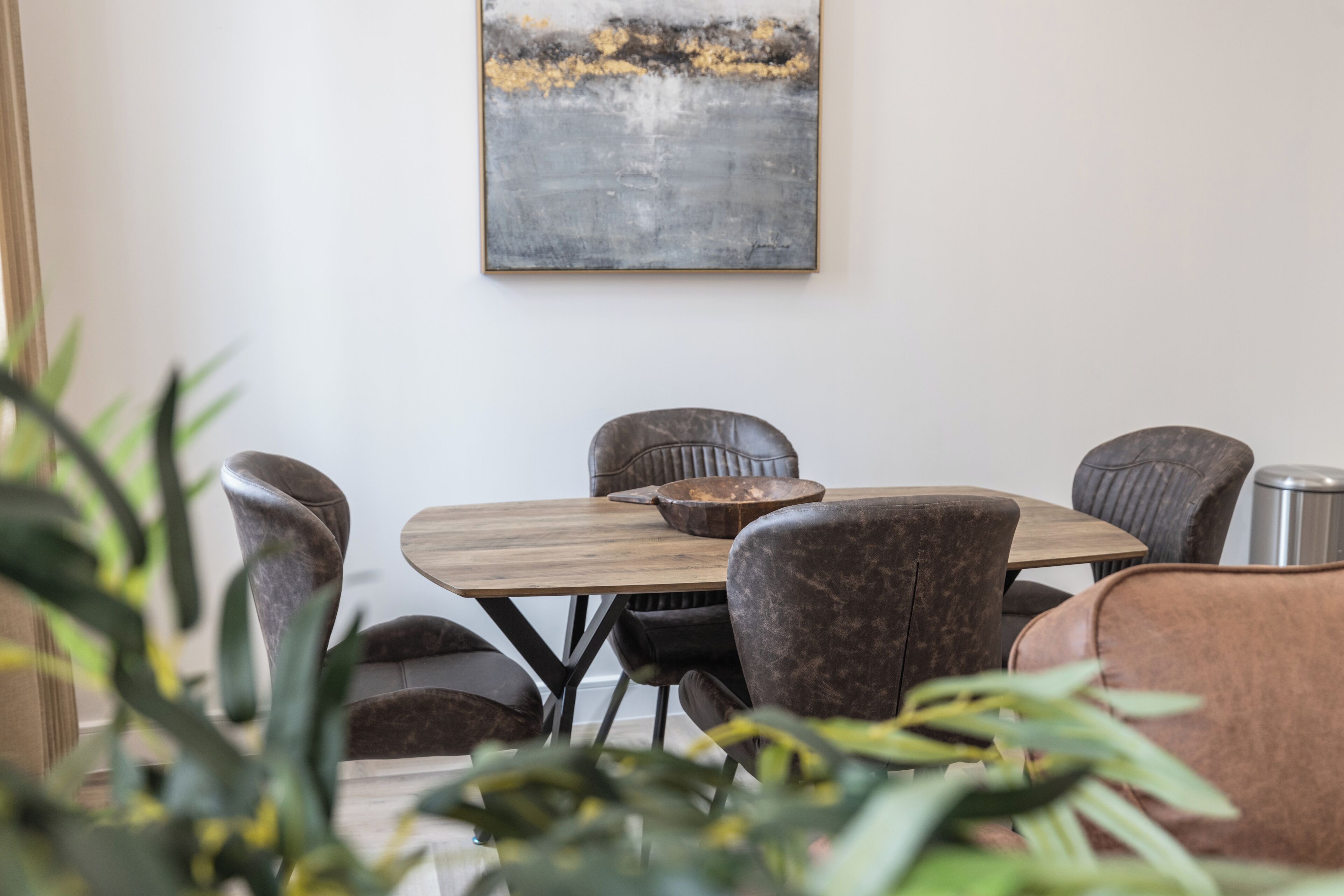 A dining area with a wooden table, leather chairs, and a bowl.