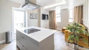 Una cocina moderna con una isla central, horno integrado y televisor montado en la pared.