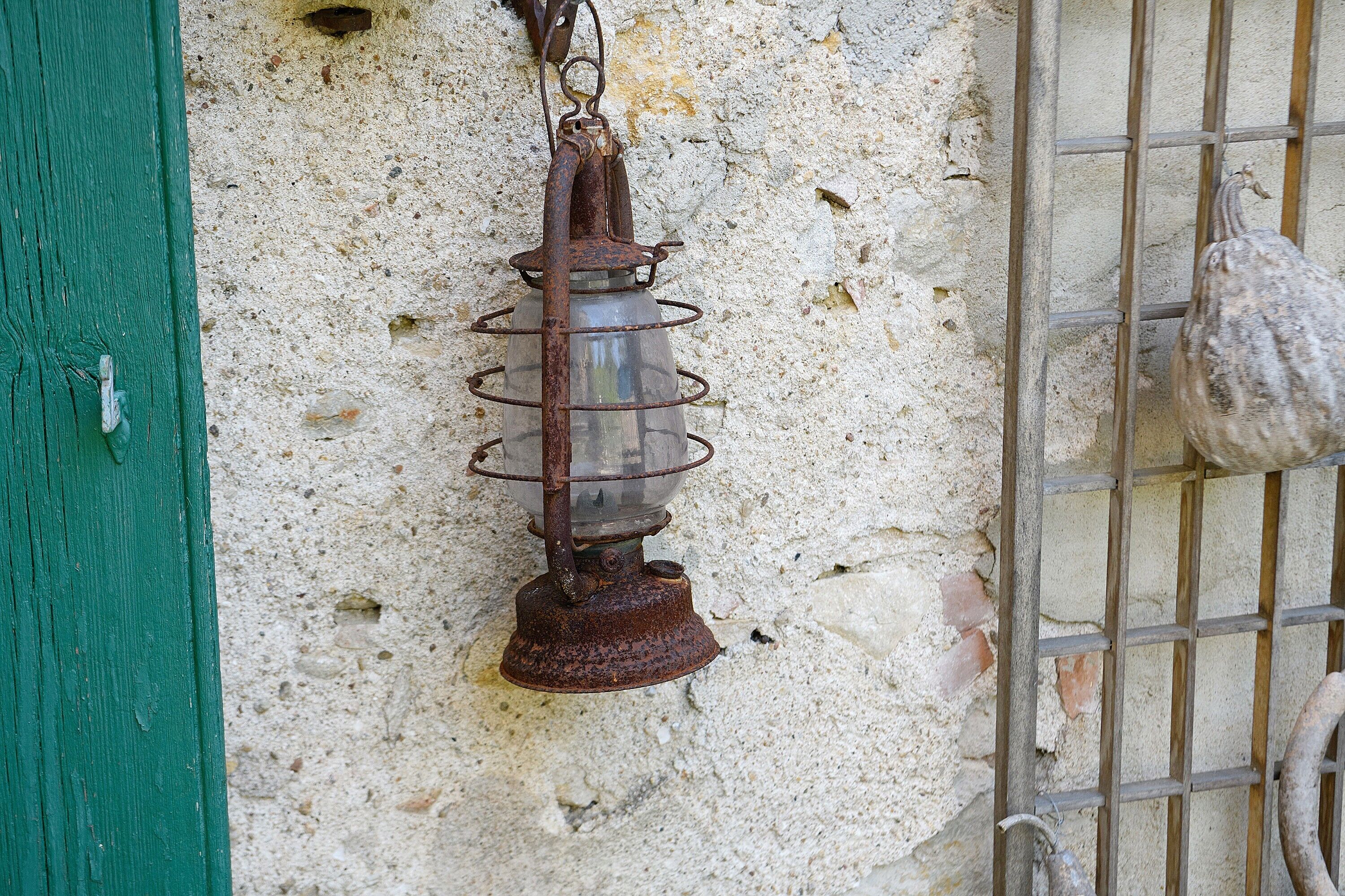 Une lanterne rustique suspendue à un mur à la texture particulière.