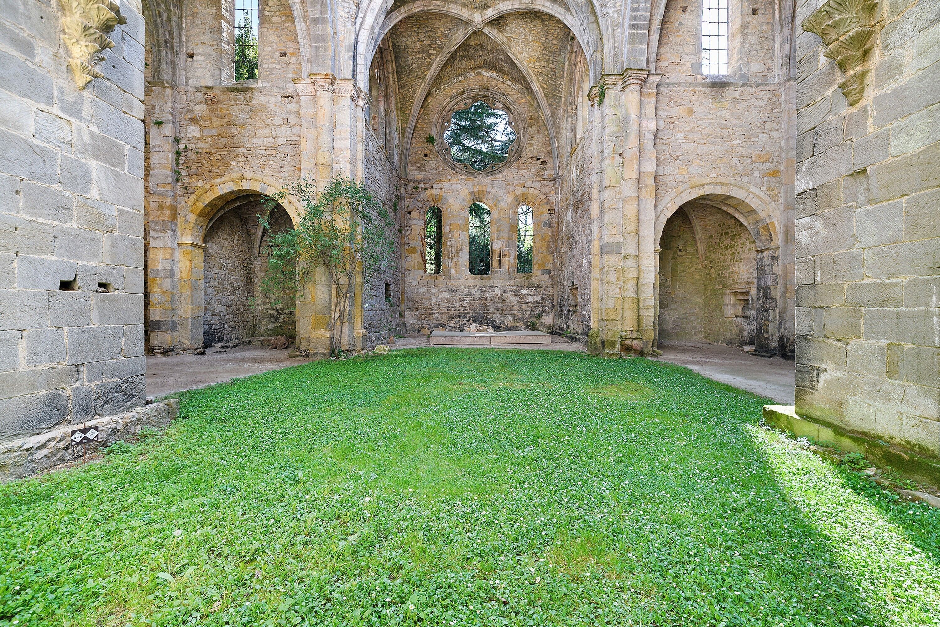 Un cortile interno con pareti in pietra, una fontana al centro e aperture ad arco.