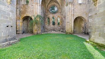 Un cortile interno con pareti in pietra, una fontana al centro e aperture ad arco.