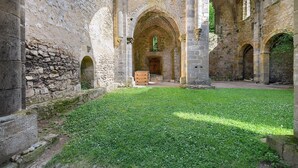 Ein Innenhof mit Steinmauern, Bögen und einer Rasenfläche.