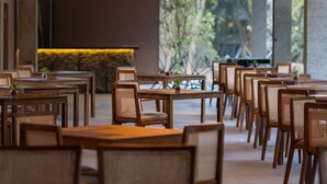 Un restaurant avec des tables et des chaises en bois, des lanternes suspendues et une vue sur la verdure environnante.