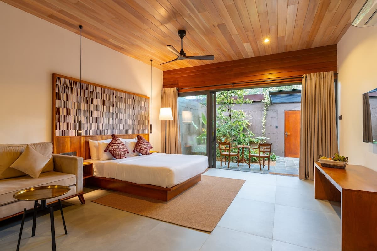 A bedroom with a bed, a sofa, a desk, and a view of the outdoors.