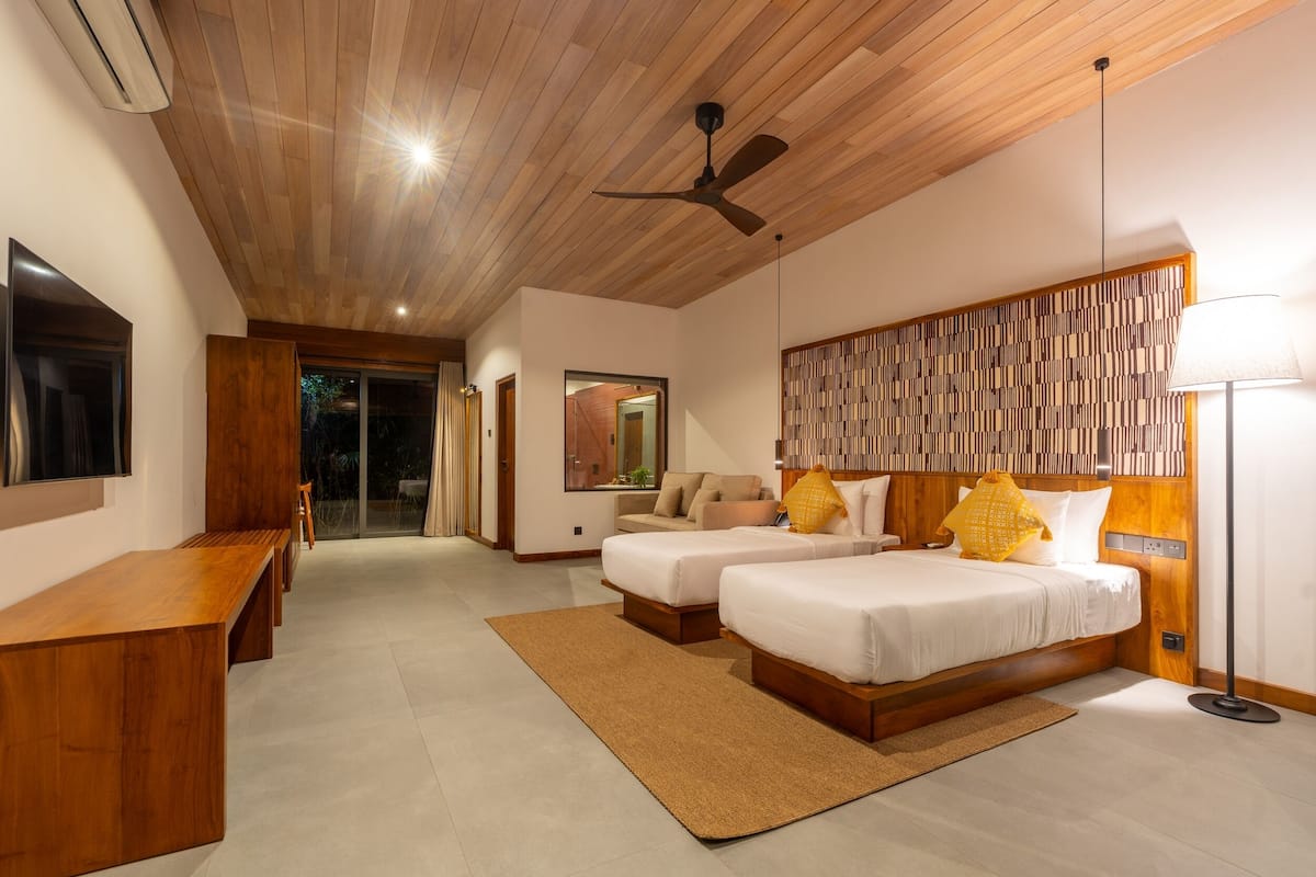 A modern bedroom with two beds, a desk, a ceiling fan, and a view of the outdoors.