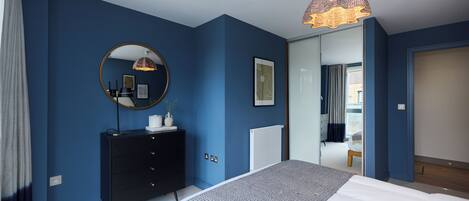 A bedroom with a large bed, a dresser, a mirror, and a unique ceiling light fixture.