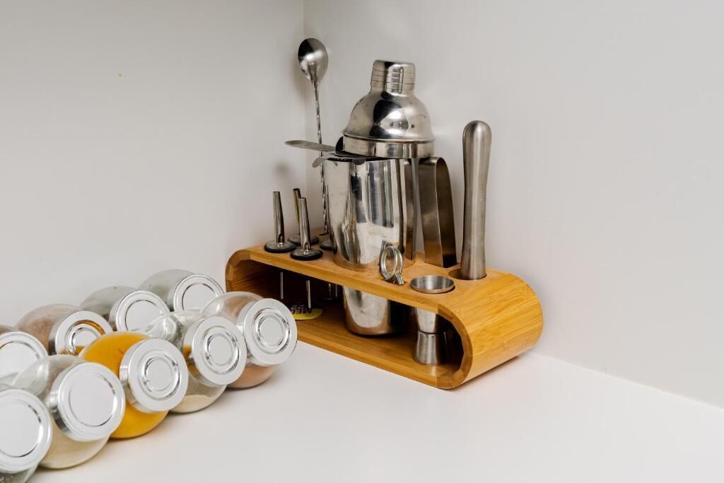 Ett cocktailshaker-set placerat på ett trästativ tillsammans med olika bartillbehör.