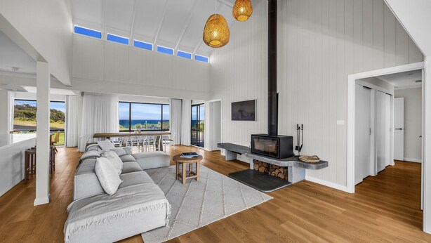 A spacious living room with a large sofa, a fireplace, and a view of the outdoors. - Fishers - Scenic Drive 35 (Bermagui)