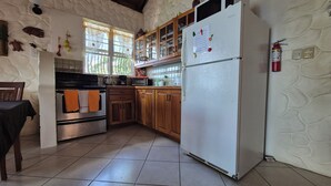 Una cocina con armarios de madera, un refrigerador blanco y piso de baldosas.