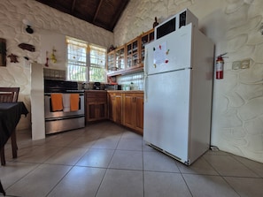 Una cocina con armarios de madera, un refrigerador blanco y piso de baldosas.