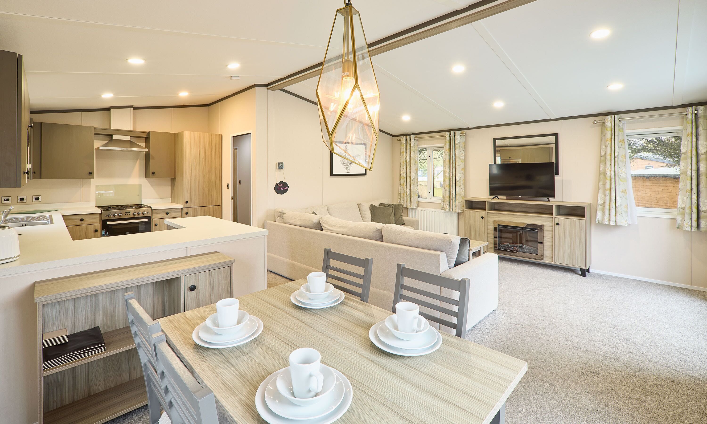 A modern kitchen with a dining area, a sofa, and a TV.
