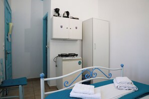 Ein Zimmer mit einem Bett, einem kleinen Schrank, einem Heizgerät und einem blauen Sessel.