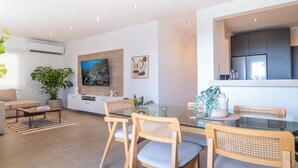 A modern living room with a glass dining table, wooden chairs, a sofa, a coffee table, a potted plant, and a painting on the wall. - Modern 3BR retreat for 6 at Tucan Country Club ⛳🌿 Enjoy golf views, resort-style living, and peaceful nature surroundings just minutes from Panama City. Perfect for families, friends, or business stays seeking comfort and privacy. ✨ (Cocoli)