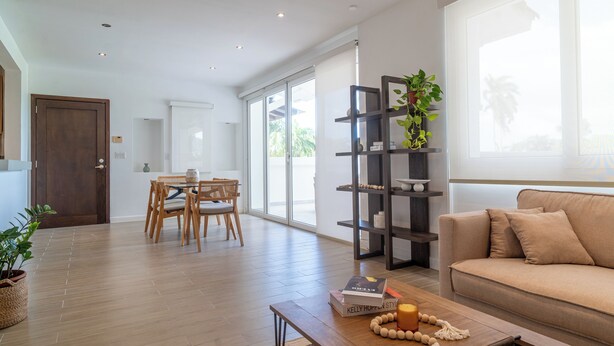 A modern living room with a sofa, a coffee table, a bookshelf, and a dining area with chairs and a table. - Modern 3BR retreat for 6 at Tucan Country Club ⛳🌿 Enjoy golf views, resort-style living, and peaceful nature surroundings just minutes from Panama City. Perfect for families, friends, or business stays seeking comfort and privacy. ✨ (Cocoli)