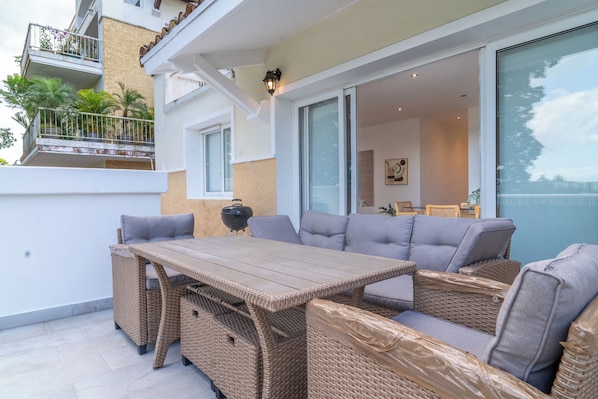 Un balcon agrémenté de meubles en osier, d’une table et d’un barbecue.