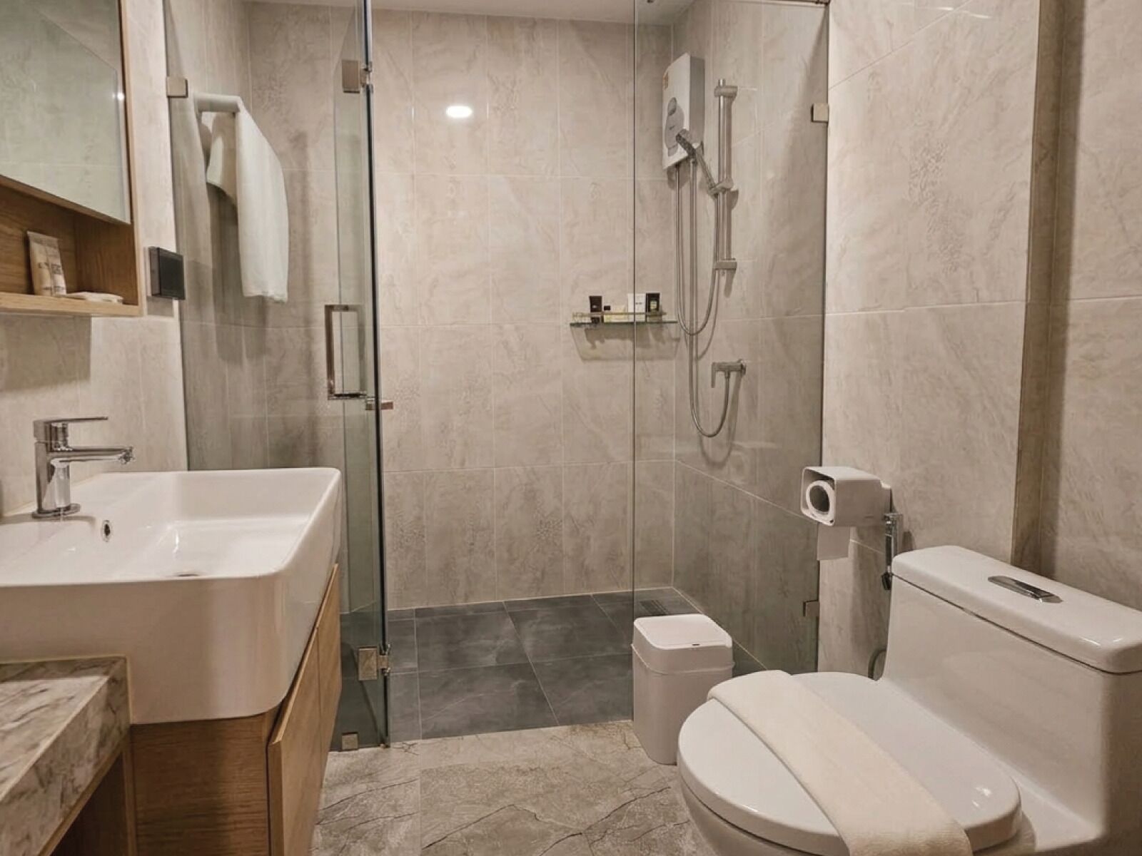 A modern bathroom with a glass shower enclosure, a toilet, and a sink.