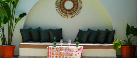 A poolside seating area with a table, two bottles, and glasses.