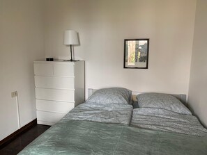 Ein Schlafzimmer mit einem Bett, einem Schminktisch, einer Lampe und einem gerahmten Bild an der Wand.