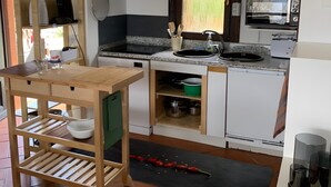 Una cocina compacta con armarios blancos, microondas, estufa y una mesa de madera con lavamanos.