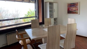 Un comedor con una mesa y sillas, un ventanal con vistas, un armario y un cuadro en la pared.