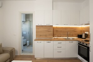 Een moderne keuken met witte kasten, een houten aanrechtblad en een ingebouwde oven.