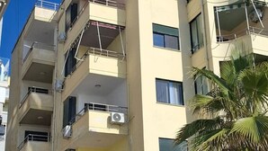 Un edificio de varios pisos con balcones, unidades de aire acondicionado y una antena parabólica.