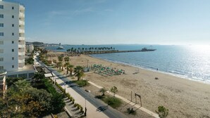 Un hotel frente al mar, con vista a la playa, un muelle y cielo despejado.