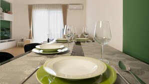 Una mesa de comedor dispuesta con platos, vasos y cubiertos en una habitación con una pared verde de acento y una ventana con cortinas.