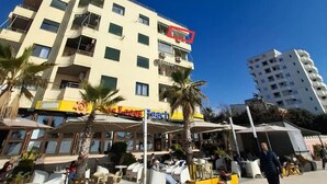 A multi-story hotel with outdoor seating and palm trees. - Greenview Apartment by Tok Apartments (Durrës)