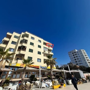 Un hôtel à plusieurs étages doté d’une terrasse et bordé de palmiers.
