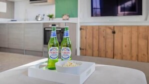 Eine moderne Küche mit zwei Peroni-Bierflaschen, einer Schüssel mit Snacks und einem an der Wand befestigten Fernseher.
