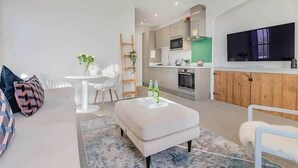 Ein modernes Wohnzimmer mit einer Couch, einem Hocker und einem flachbildfernseher an der Wand.