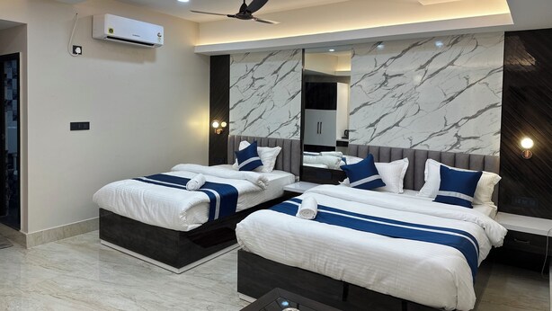 Quarto de hotel moderno com duas camas, ventilador de teto, iluminação embutida, um espelho grande e detalhes de parede em mármore.