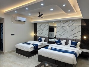 Habitación de hotel moderna con dos camas, ventilador de techo, luces empotradas, un espejo grande y detalles de pared de mármol.