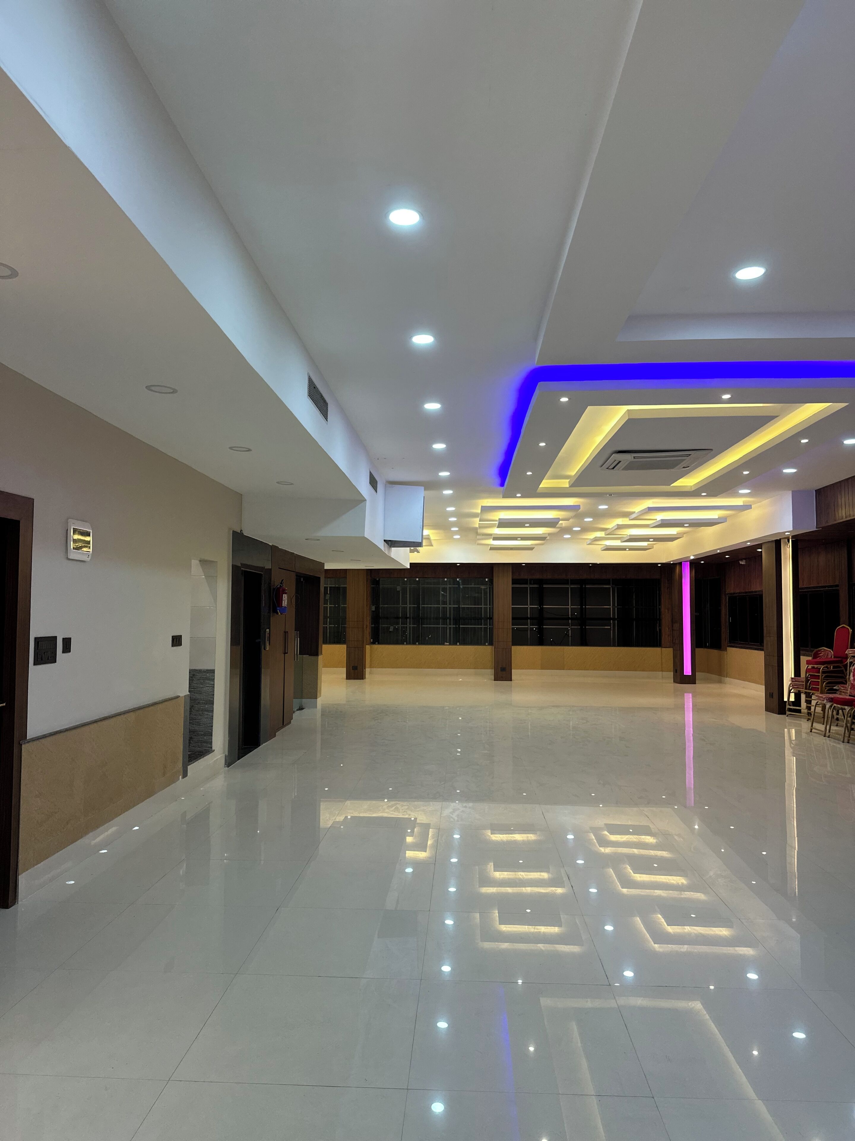 A spacious lobby with a polished floor, recessed lighting, and a modern ceiling design.