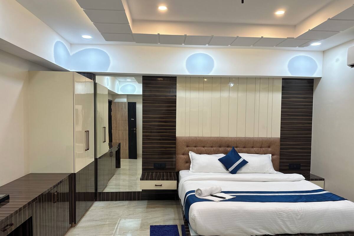 A modern hotel room with a large bed, a vanity with a mirror, and a walk-in closet.