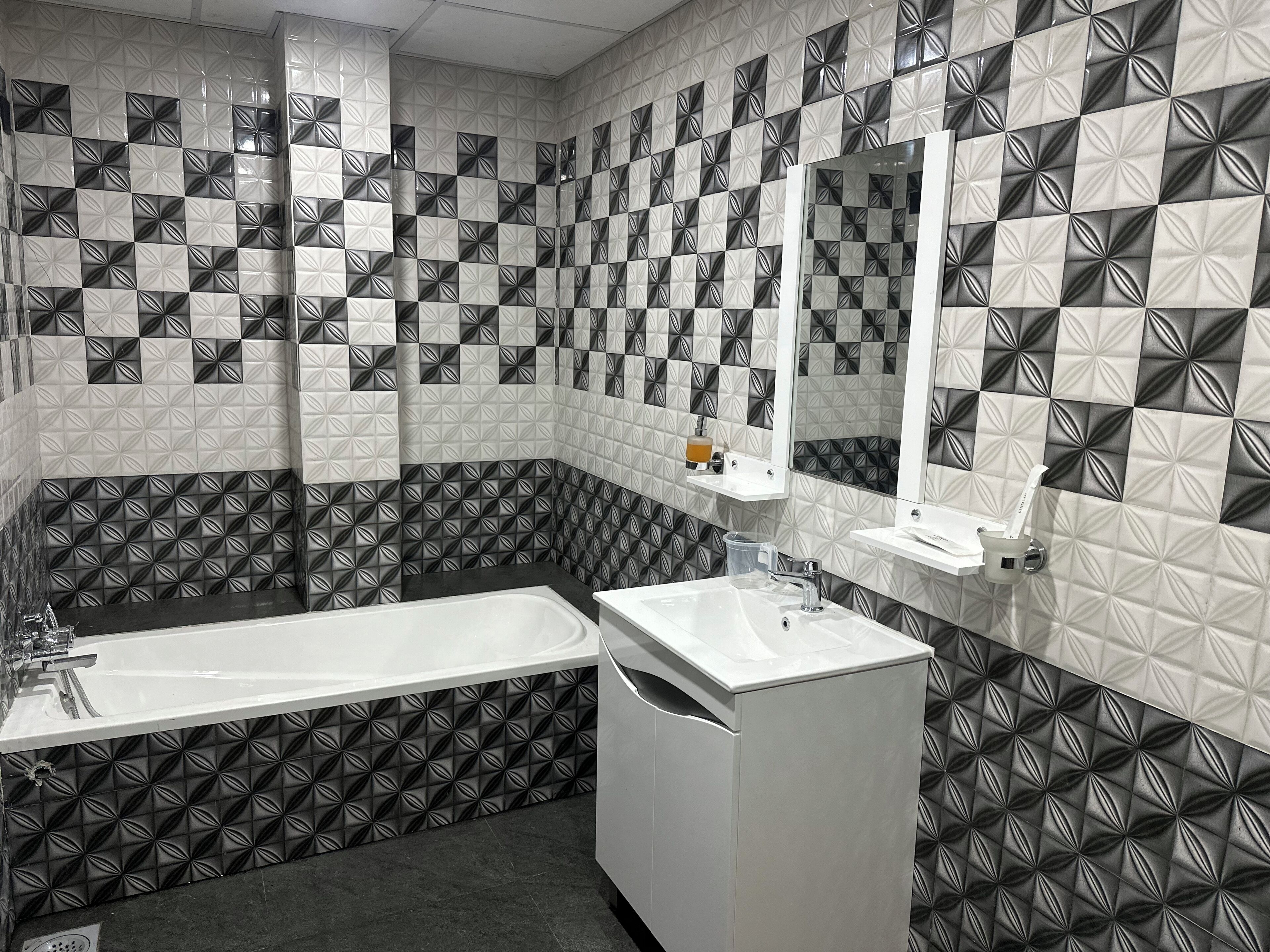 A bathroom with a bathtub, a sink, and a mirror.