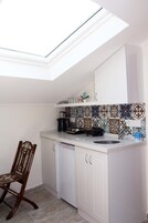 Eine kompakte Küche mit Dachfenster, weißen Schränken und einer gemusterten Spritzschutzwand.