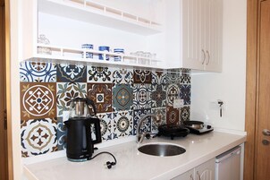 Uma cozinha com azulejos estampados, uma cafeteira, uma pia e armários.