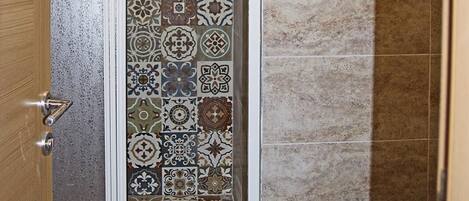 A bathroom with a shower area featuring a tiled wall with a variety of patterns.