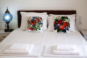 A neatly made bed with two embroidered pillows, a bedside lamp, and a white brick wall. - Lara Apart (Datca)
