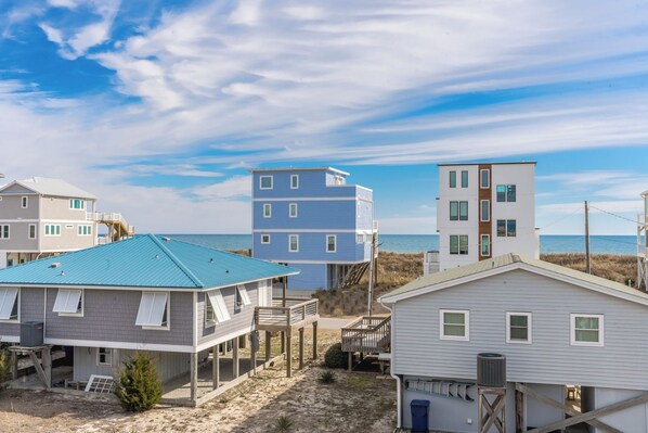 A beachfront property with multiple buildings, including a blue two-story house and a white single-story house. - Beachside Bungalow - Dog Friendly - Amazing views from rooftop deck! (Topsail Beach)
