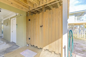 A wooden structure with a door, a small step leading to a porch, and a hose on the right. - Beachside Bungalow - Dog Friendly - Amazing views from rooftop deck! (Topsail Beach)