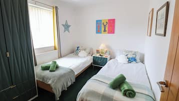 A bedroom with two single beds, a nightstand, a star decoration, and a wall with colorful artwork.
