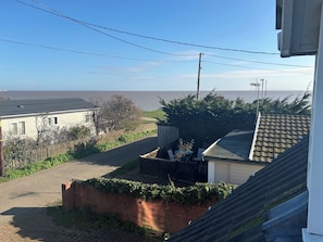 A residential area with a paved road, a wooden fence, and a view of the sea. - Seaview (Lowestoft)