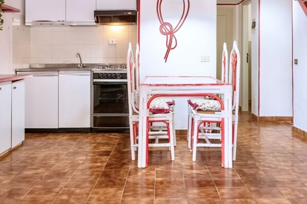 A kitchen with white cabinets, a stove, and a dining table with white chairs.