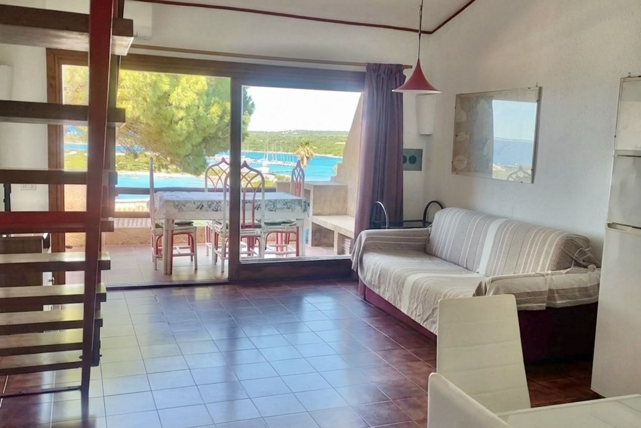 Una habitación con cama, una mesa con sillas, vista a una piscina y un balcón.