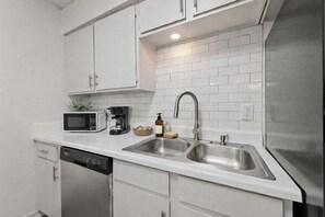 A compact kitchen with white cabinetry, a stainless steel sink, a microwave, and a coffee maker. - Arlington 2BR • Walk to AT&T • Free Parking (Arlington)