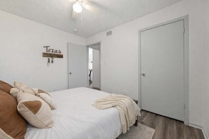 A bedroom with a bed, a door, and a wall-mounted sign. - Arlington 2BR • Walk to AT&T • Free Parking (Arlington)